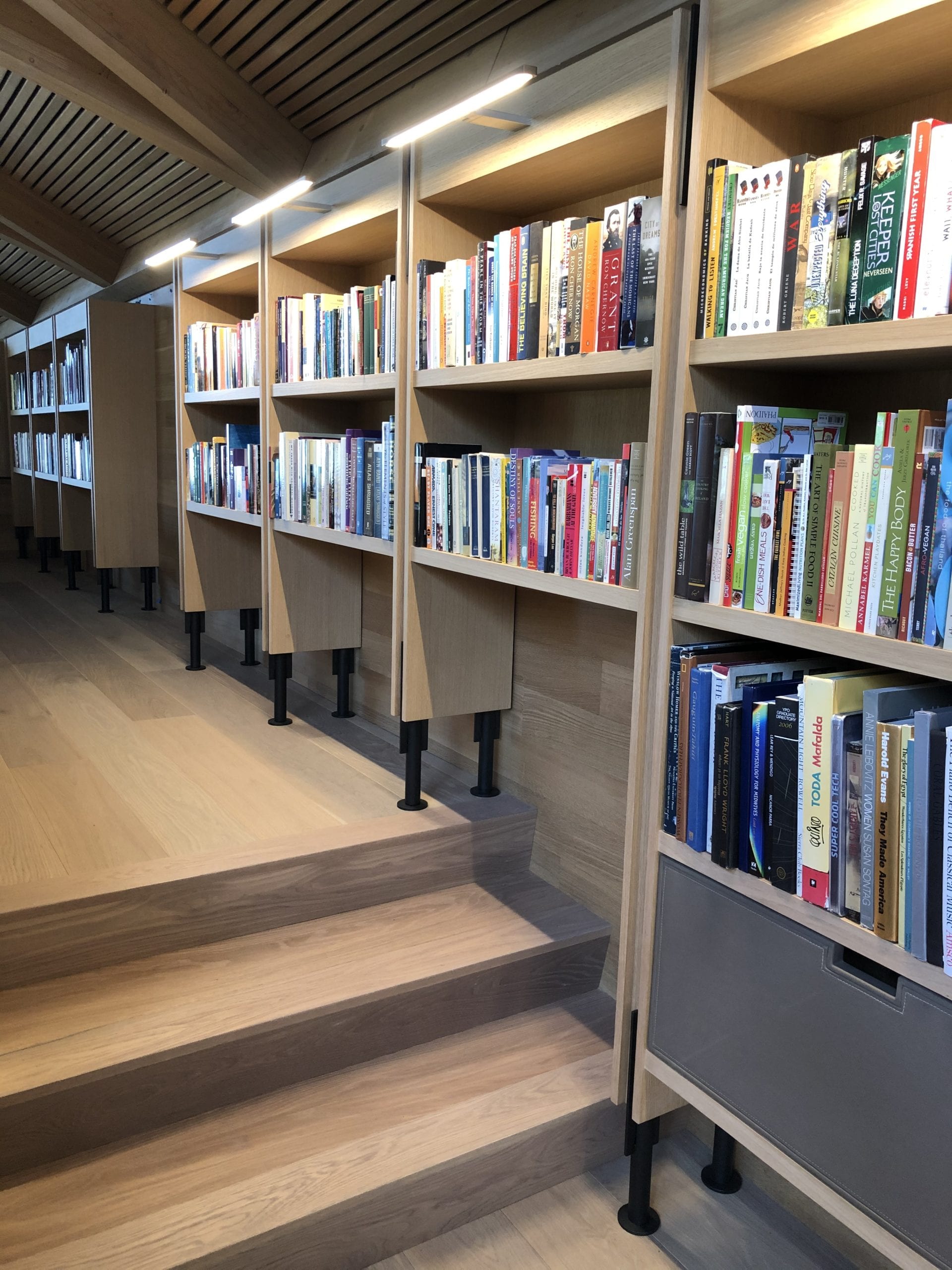 Custom stepped library shelving with warm wood details
