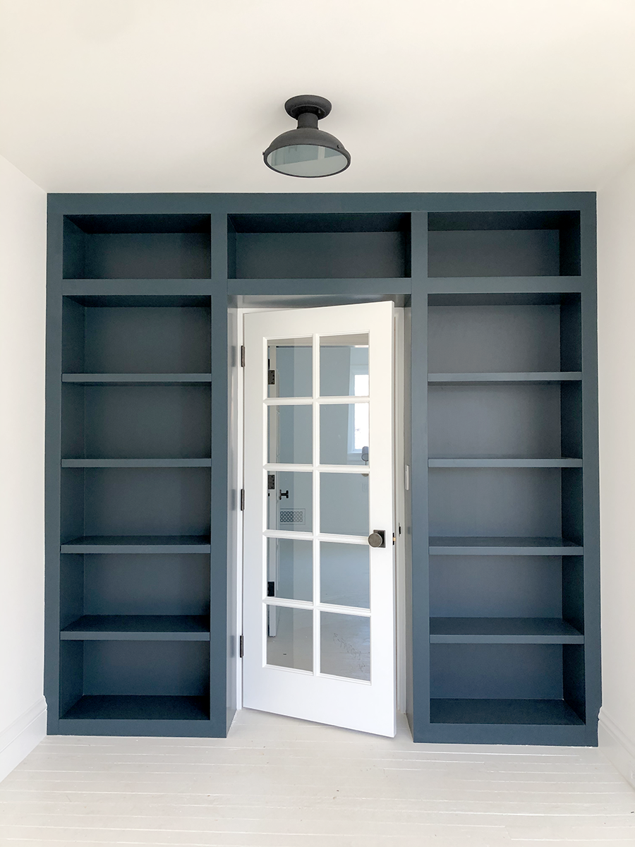 Dark blue built-in bookcase surrounding a glass-paneled door