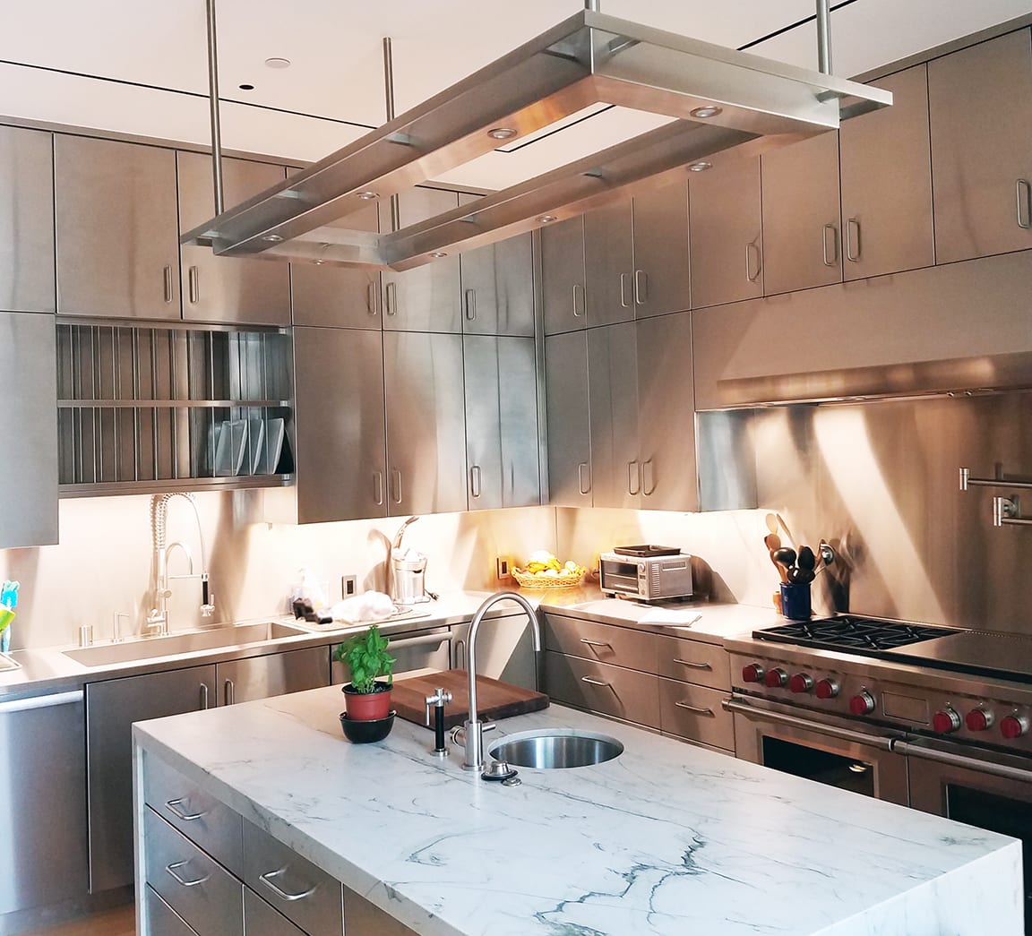Custom stainless steel kitchen cabinetry and marble island